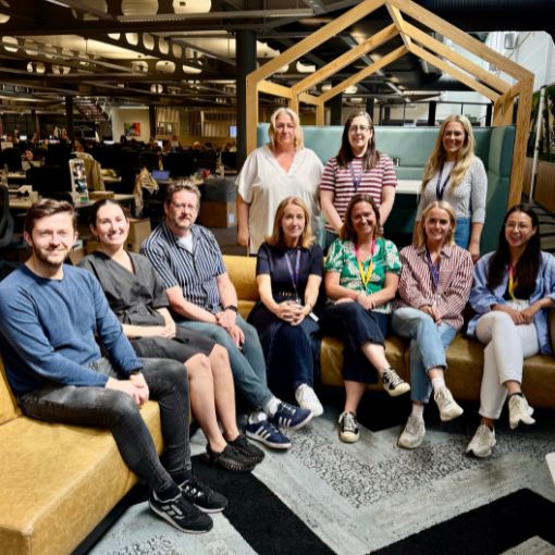 A group of colleagues sat together in a break out space at an office.