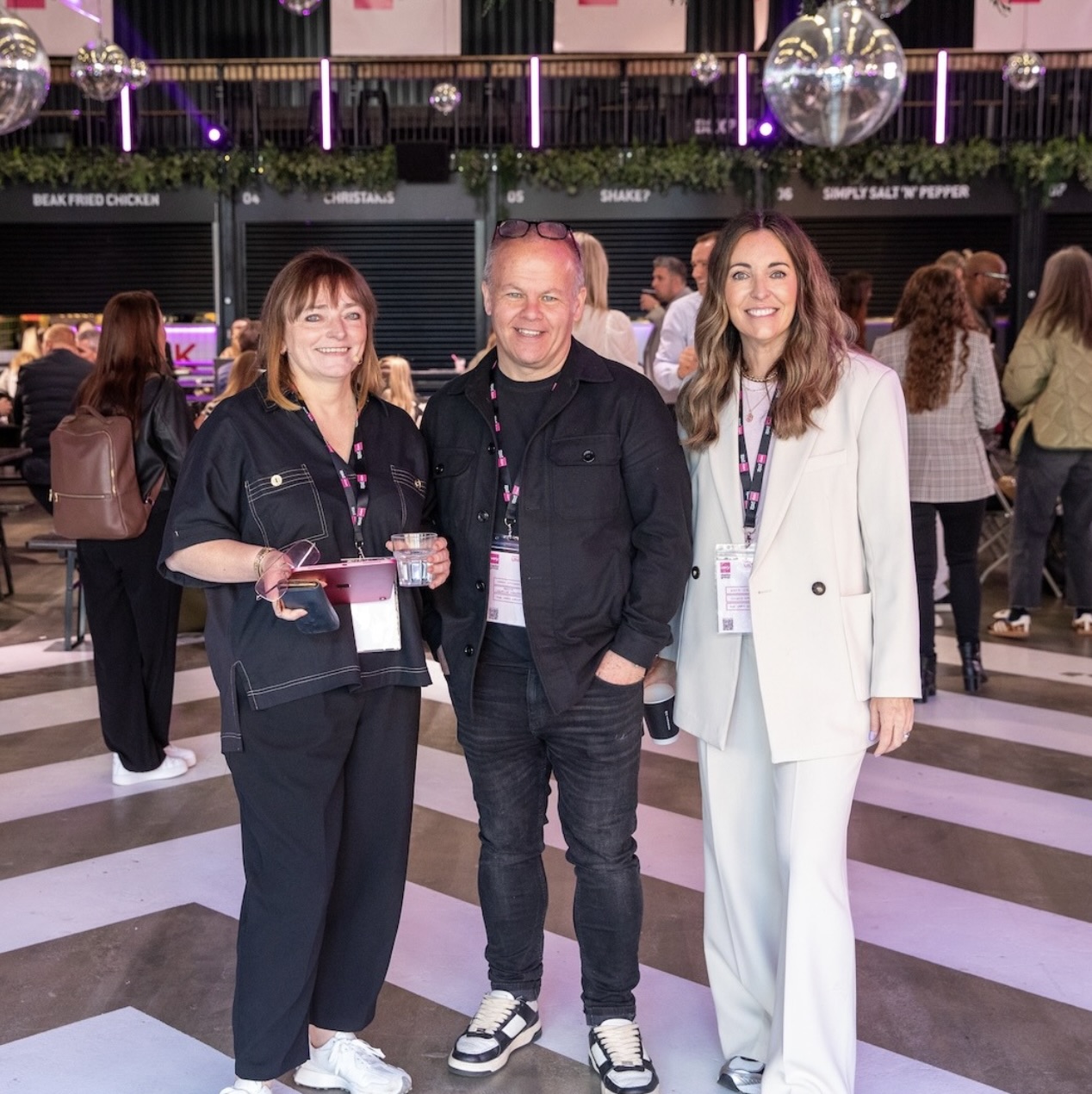 Two women and a man stood together at an inside event.