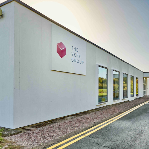 Exterior photo of a white building with 'The Very Group' branding on the side.